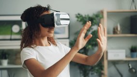 Portrait of happy African American girl using virtual reality glasses moving hands and smiling then taking headset off and looking at camera with smile. Youth and gadgets concept.