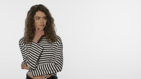 Thoughtful woman looking at white background. Pensive girl thinking about product in studio. Portrait of doubting person estimating product. Young people scepticism concept