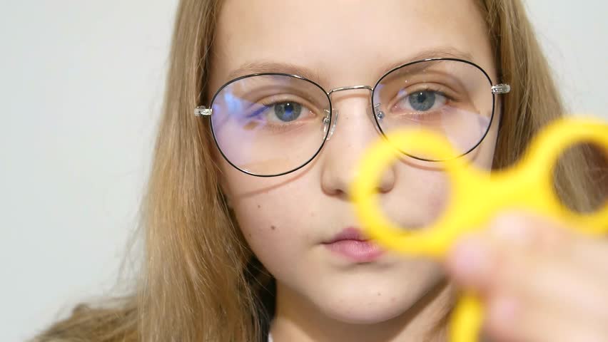 Girl playing with a fidget spinner, girl with glasses spinning spinners. 4k video | Shutterstock HD Video #1025666192