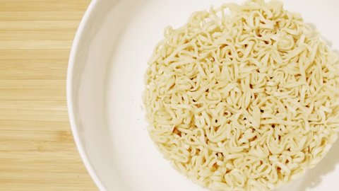 Adding hot water to instant noodles, top down view. Slow motion shot