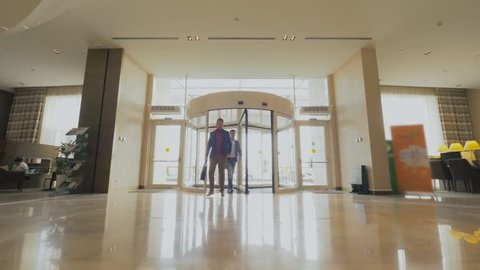 Business men coming into revolving doors in modern business center. Business people entering in lobby and walking on hallway in luxury hotel. France, Paris - November, 2018.