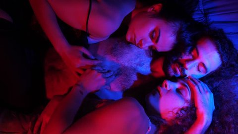 Three young people kissing in bed.Polyamory,Poligamy,Threesome