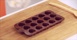 Close up scene video of someone squeeze white chocolate into  heart shaped chocolate mold, concept for made chocolate for Valentine's day.
