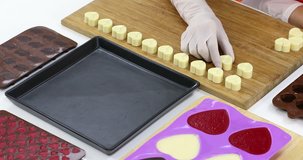 Close up scene video of someone arranged heart shaped white chocolate on a tray.
