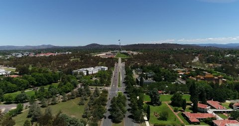 Commonwealth avenue in Canberra leading to Capitol hill with federal lawmaking building of national parliament under Australian flag.
