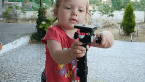 Baby playing with a monopod, kid is walking and exploring the monopod