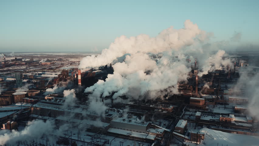 Drone extremely near flight between several steel plant tubes through the clouds of smoke, industrial park landscape in winter snowy evening, air emissions from manufacturing sector, Chelyabinsk Royalty-Free Stock Footage #1025675336