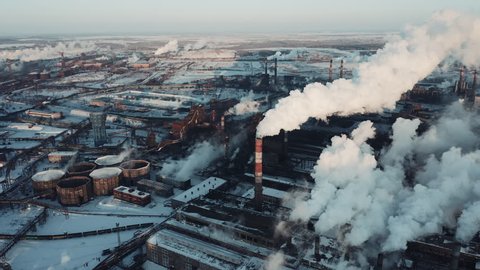 Drone panning of industrial park, many smoke stack pipes of steel plant, technogenic landscape in winter sunny evening, concept of pollution, air emissions from manufacturing sector, industrial city