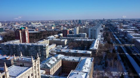 Aerial; drone panoramic view of Chelyabinsk snow cityscape; winter city forest with pine trees on background; main street with cars; center of science and development; education system of engineering