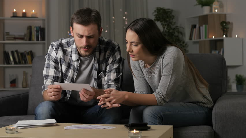 Worried couple checking bank receipts sitting on a couch in the night at home Royalty-Free Stock Footage #1025676314
