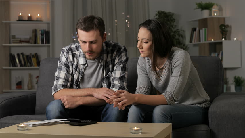 Worried couple reading a letter sitting on a couch in the night at home Royalty-Free Stock Footage #1025676320