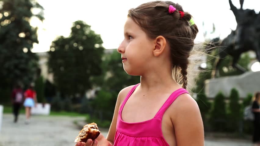 Little girl eating a bun on the street