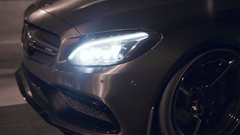 Bucharest, Romania-11.03.2018: Close up moving rolling shot of a custom C63 AMG driving on a city street at night