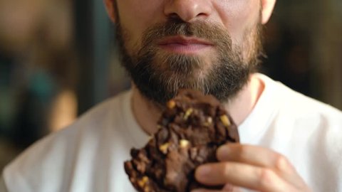 Man eats a chocolate chip cookies in a cafe