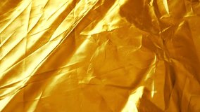 Background of golden synthetic crumpled fabric. close-up. fabric texture. light-reflecting fabric