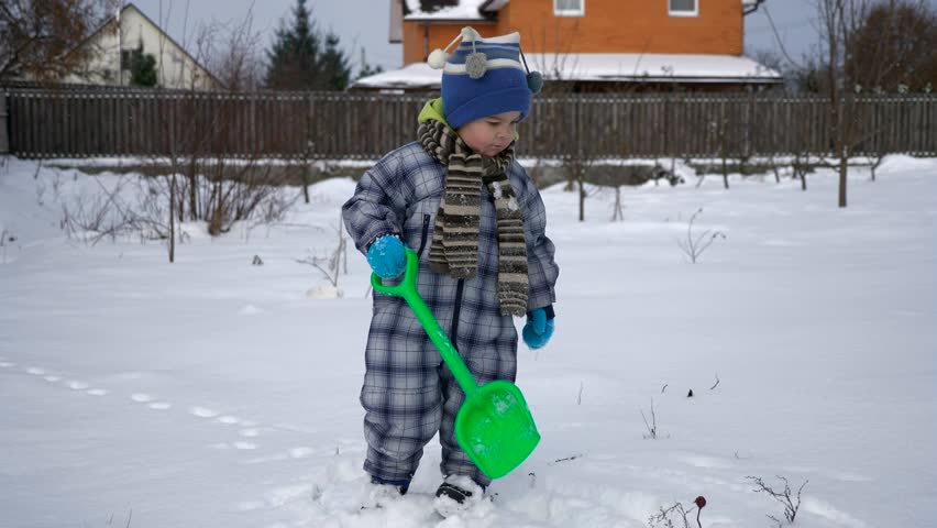 Cute Little Child In Warm Clothes Walks Outdoors On Snow On Backyard. Sunny Winter Day Slow motion 0.5 speed 60 fps