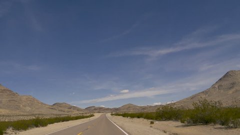 Driving the Great Basin Highway, US 93 in Nevada Passing desert hills under blue sky-DrivePlate-POV-View Forward