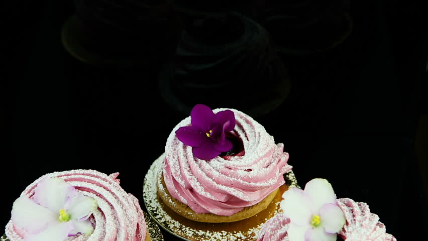 closeup panorama down on small group of pink marshmallow cookies decorated with violet and white flowers