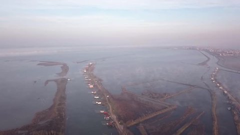 Aerial view at dawn of the Comacchio lagoon in the Po river Delta park. You can see fishing huts and small low clouds