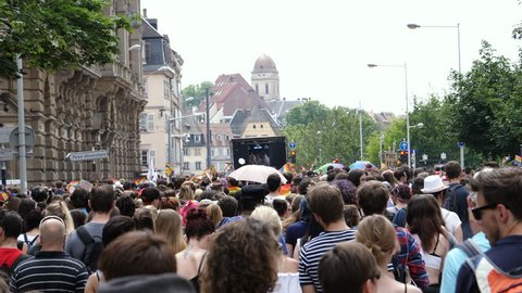 STRASBOURG, FRANCE - CIRCA 2018: People walking following gay truck crowd people waving rainbow flags at annual FestiGays pride gays and lesbians parade marching French streets fun party atmosphere