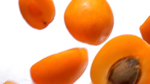 Halves ripe apricots fly close-up on white background in slow motion