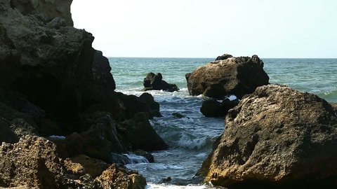 Rocks about which break sea foamy waves