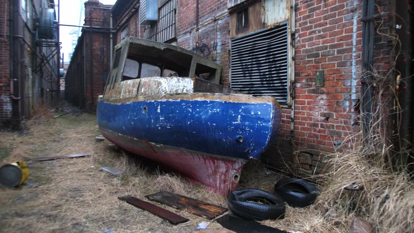 Damaged Boat in Abandoned Shipyard Area with Industrial Brick Buildings