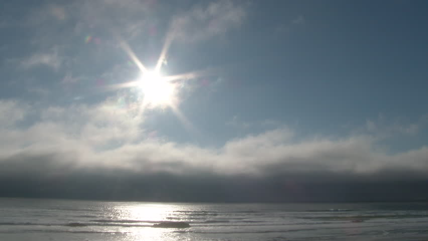 Sun shining on blue sky day with fast moving clouds passing over the Pacific Ocean at the Oregon Coast in Lincoln City.