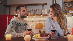 Cheerful lovely couple drinking wine while spending romantic evening together at home