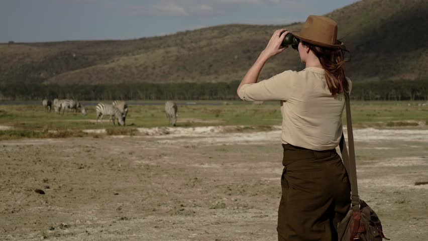 Woman spottings wild animals at savanna in Kenya