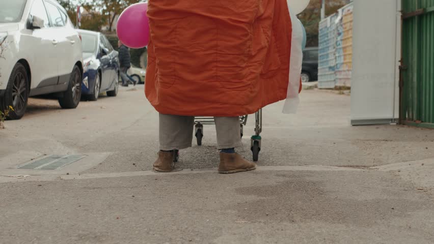 Homeless man out on the streets with his belongings in a trolley. Bum legs walking street with shopping trolley