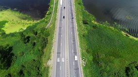 4k. Aerial drone footage. Cars drive on the highway located between the blue lake. The sky is reflected in the blue water. Magic Valley, green forest on the horizon.