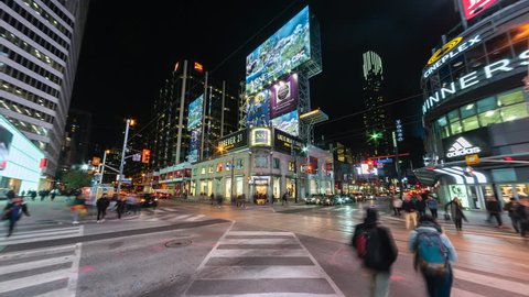 Toronto, Canada - October 22, 2018: Time lapse view of people and traffic crossing busy intersection at Yonge and Dundas Square at night in Downtown Toronto, Ontario, Canada.