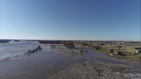 The Platte River in Nebraska swells to historic, record levels. The rushing waters nearly over take a highway and spill into adjacent farm fields and residential areas. Filmed using drone. 