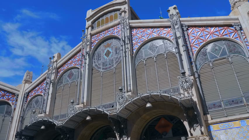 Central Market of Valencia is beautiful historical building in the city of Spain with individual classic national design against the blue sky with clouds. Shot in motion