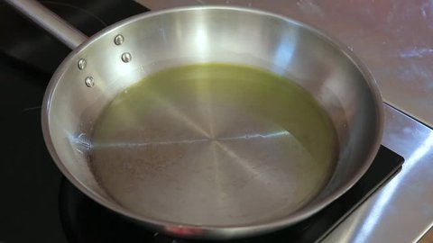 Hands throwing cut onion and garlic into the hot frying pan with oil 