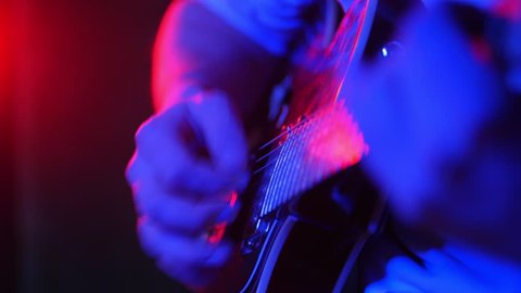 A person playing guitar in neon lighting