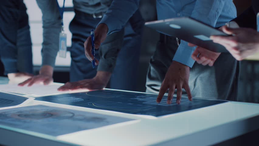 Engineer, Scientists and Developers Gathered Around Illuminated Conference Table in Technology Research Center, Talking, Finding Solution and Analysing Industrial Engine Design. Close-up Hands Shot | Shutterstock HD Video #1025767421