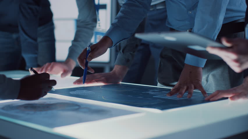 Engineer, Scientists and Developers Gathered Around Illuminated Conference Table in Technology Research Center, Talking, Finding Solution and Analysing Industrial Engine Design. Close-up Hands Shot | Shutterstock HD Video #1025767421