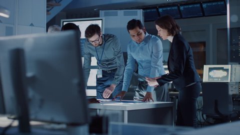 Engineers Meeting in Technology Research Laboratory: Engineers, Scientists and Developers Gathered Around Illuminated Conference Table, Talking and Finding Solution. Shot on 8K RED