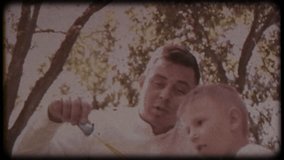 Family video archive. Retro camera 8 mm. Old film. Father with his son blowing soap bubbles, fun family pastime, a child having fun with his dad