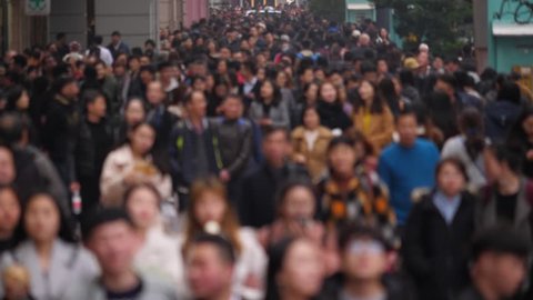 Pedestrian street filled with people, blurred version of footage, showing anonymous citizens walking at Nanjing Road. Citizens and tourists stroll around famous shopping and dinning area of Shanghai