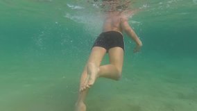 Cheerful cute white kid learning to swim during beach summer vacations. Video shoot underwater with action camera.