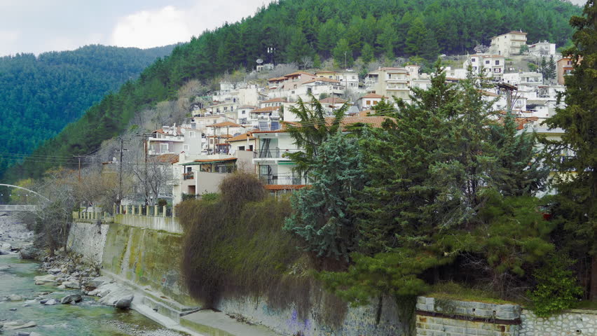 Xanthi, Greece old town hill view of houses by Kosynthos river. Day city view of low rise buildings with roof tiles on right bank of rocky river bed with water running in Eastern Macedonia and Thrace.