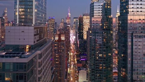 Aerial drone footage of New York skyline along 42nd street canyon, at dusk, with pull back camera motion