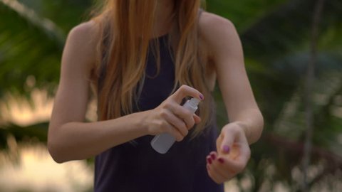 Closeup shot of a beautiful young woman applying an antimosquito repellent spray on her skin. A tropical background. Mosquito defense concept