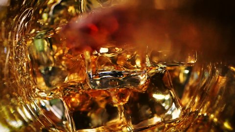 Whiskey poured into a glass with ice. On dark background. Top view.
