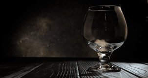 Cognac is poured into a glass. On dark background. 4k.