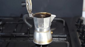 In the frame, the Italian moka coffee maker is taken close up, the lid is open a inside the coffee maker can be seen as freshly brewed coffee boils and steam comes out