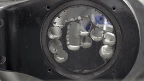 Very closeup video recording of a dental milling machine working process. Hi-speed spindle with water cooling is carving on a titanium disc. Water splashing and dripping around.